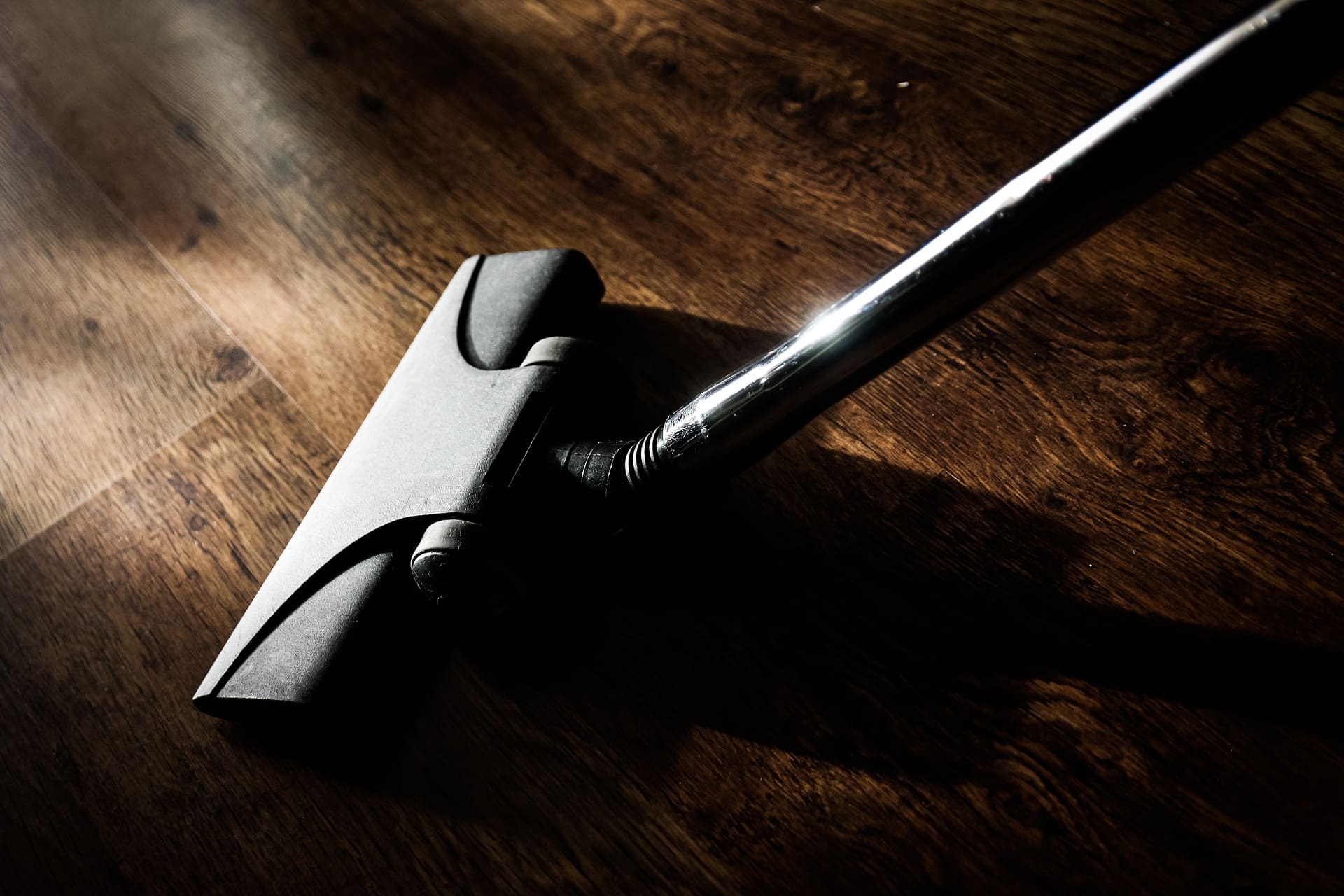 A close up of a black and silver handle on a wooden floor